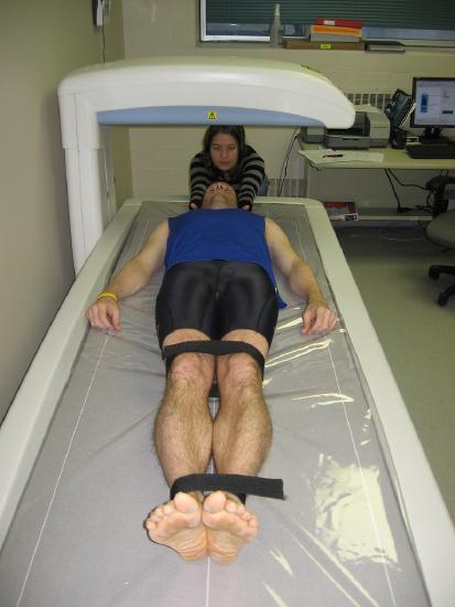 Image of a person laying on a medical table with the DEXA scanner positioned above their body.