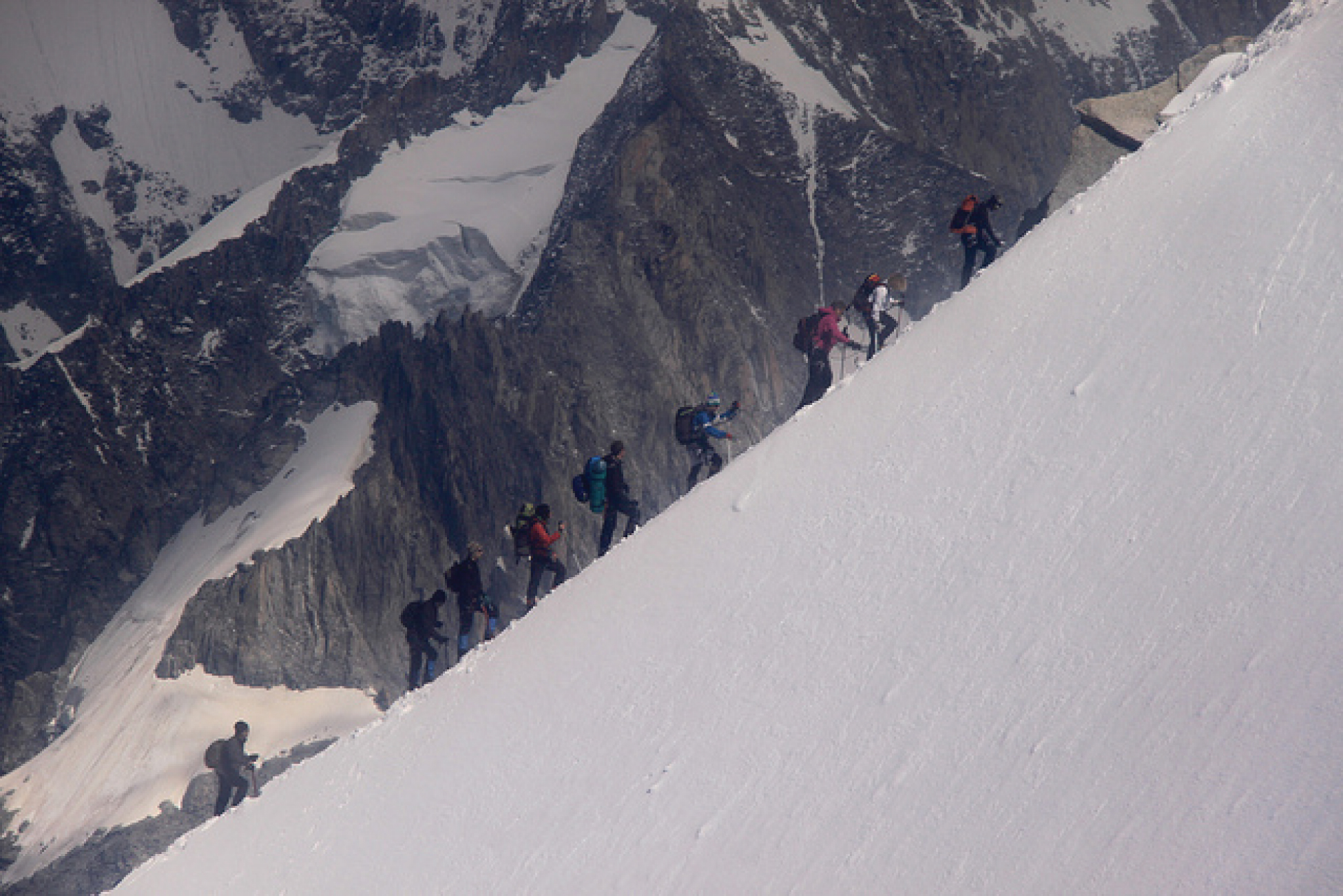 Mountain climbers ascending a snowy ridge in the French Alps.