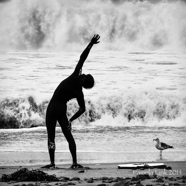 Silhouette of person stretching in front of ocean waves