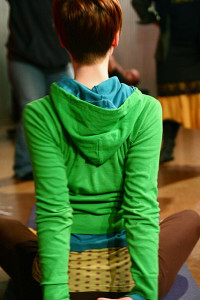 Person in green hoodie stretching arms down behind back