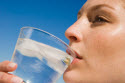 Woman drinking water against blue sky