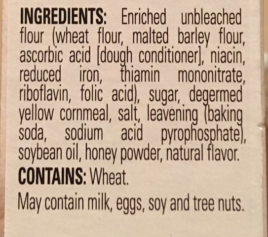 A photo of the ingredients listed on a cornbread mix. It reads "INGREDIENTS: Enriched unbleached flour (wheat flour, malted barley flour, ascorbic acid [dough conditioner], niacin, reduced iron, thiamin mononitrate, riboflavin, folic acid), sugar, degermed yellow cornmeal, salt, leavening (baking soda, sodium acid pyrophosphate), soybean oil, honey powder, natural flavor. CONTAINS: Wheat. May contain milk, eggs, soy and tree nuts.