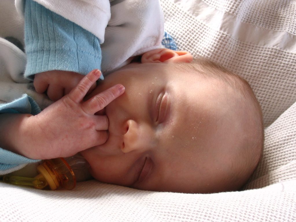 Photo of an infant sucking on its own fingers