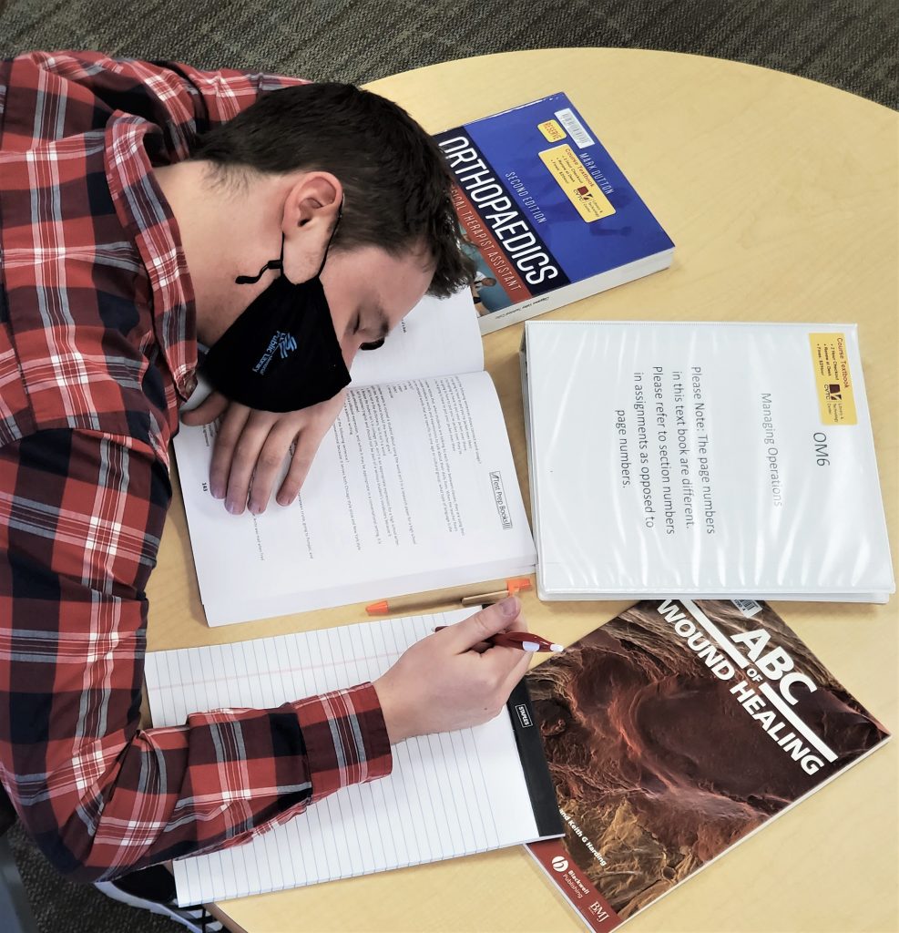 Image showing a student sleeping, with head resting on their open textbooks