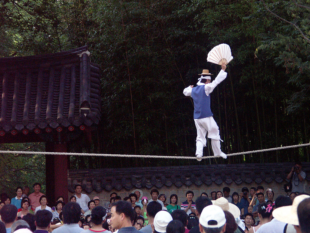 A man balancing on a tightrope over a crowd of people.