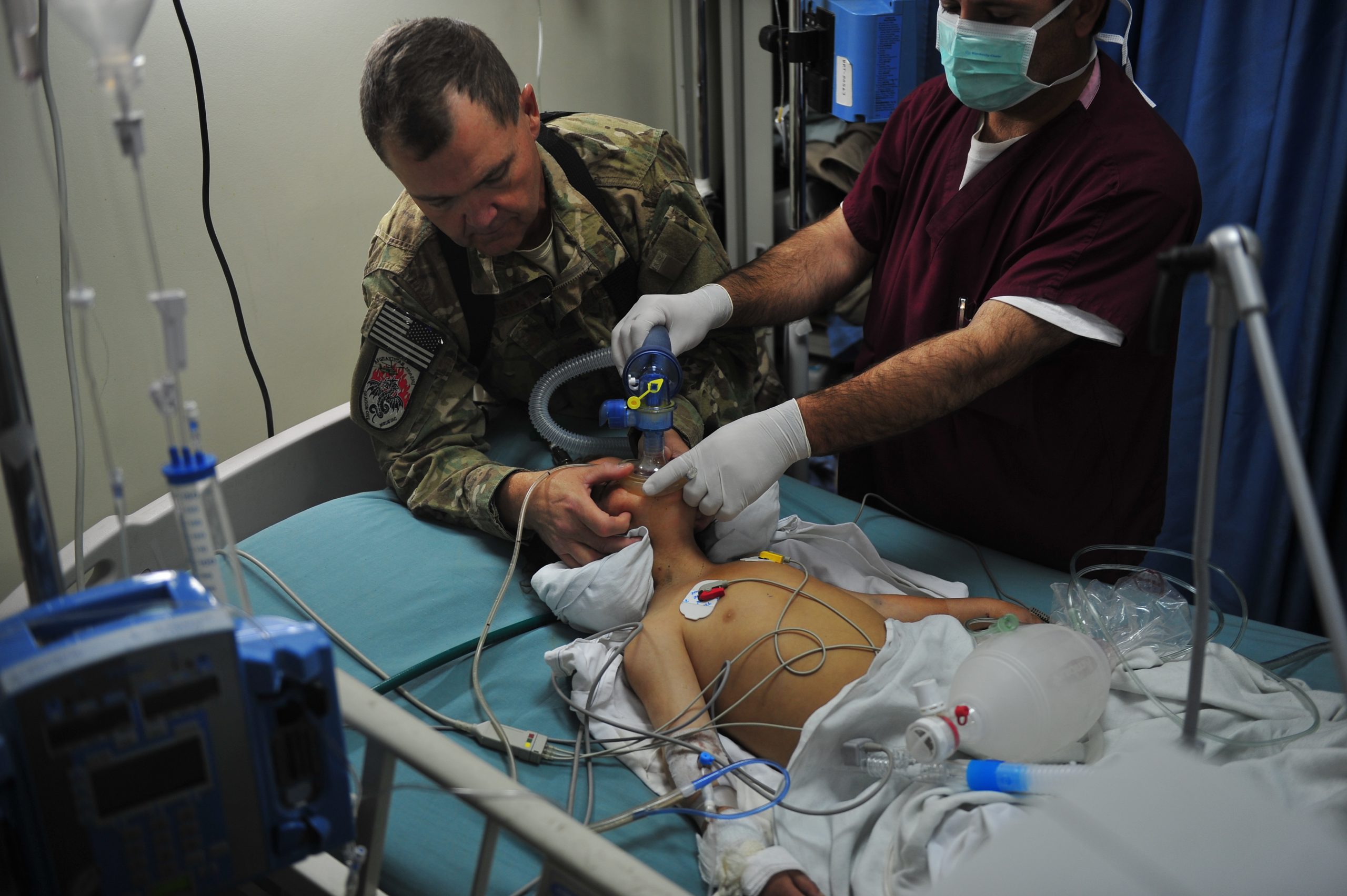 Photo showing an Air Force critical care nurse assisting a doctor in helping a child breathe