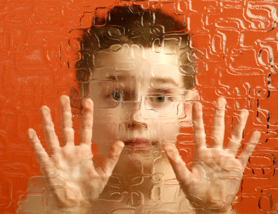 Foto que muestra a un niño mirando a través de un vidrio ondulado al espectador