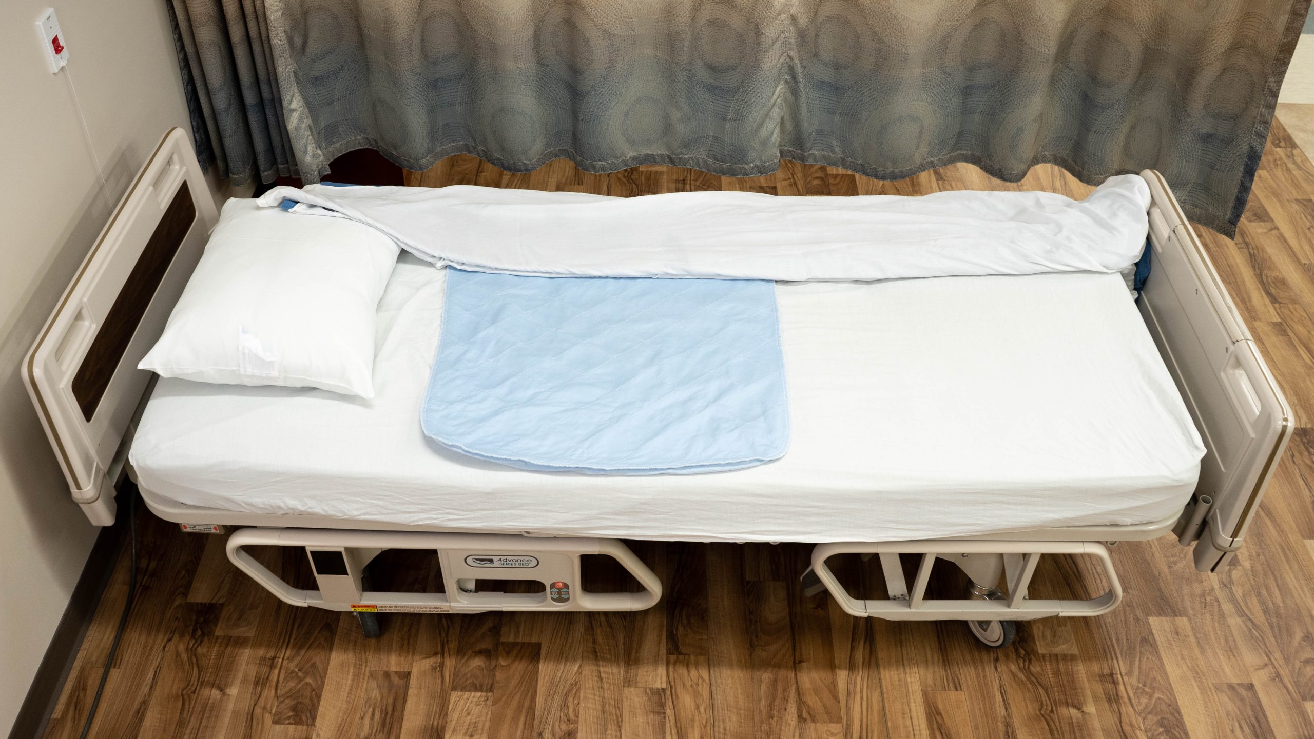 A bed made with the sheets pulled to one side for easy transferring from a stretcher.