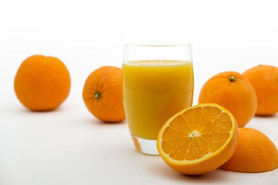 Glass of orange juice and some oranges on a table