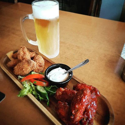 Restaurant plate with breaded and barbecue chicken wings and a tall mug of beer. 