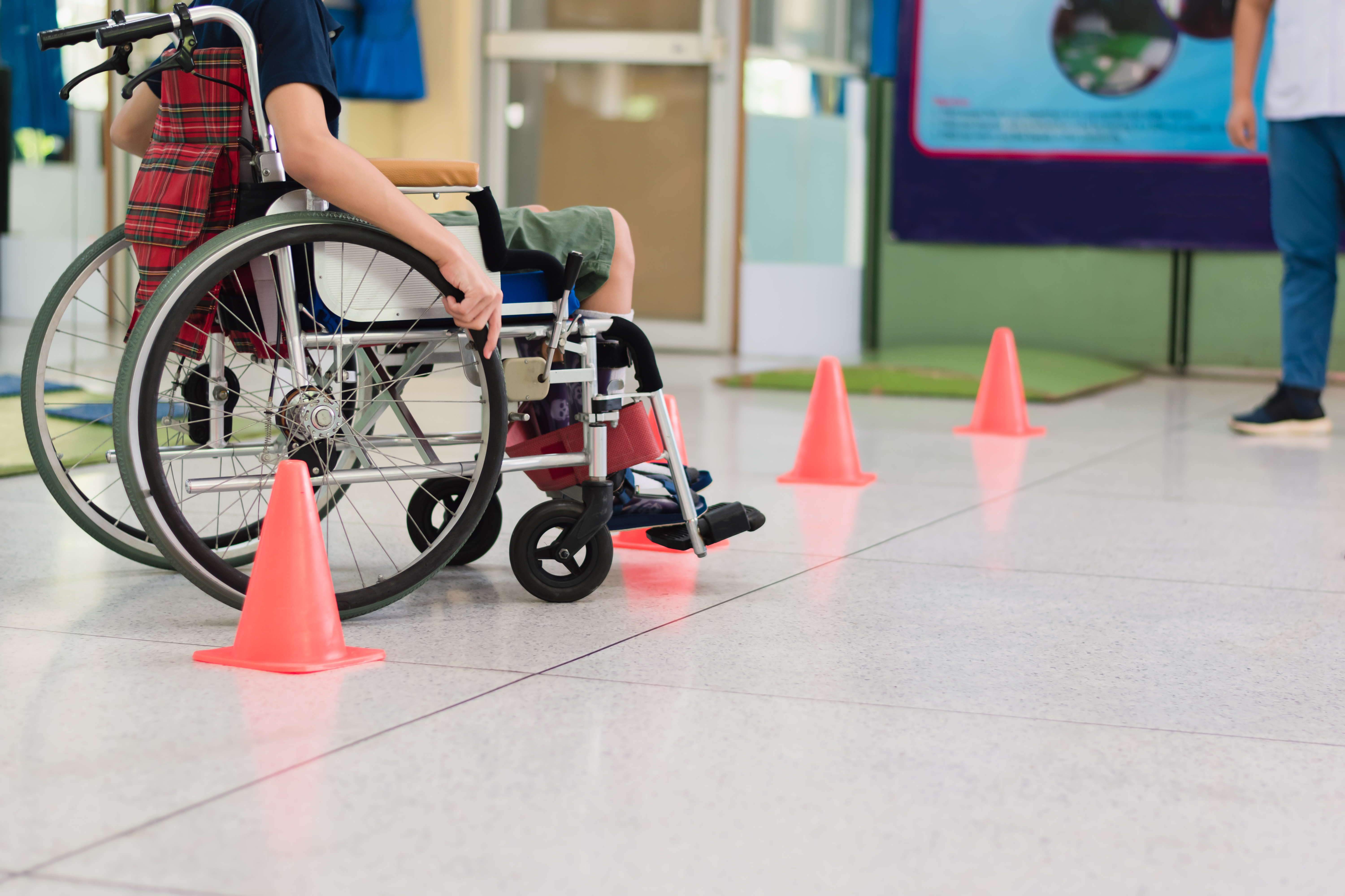 Special need child practicing wheelchair by an occupational therapist teacher on ramps for people with disabilities