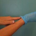 Insertar el dedo debajo del puño de la mano enguantada