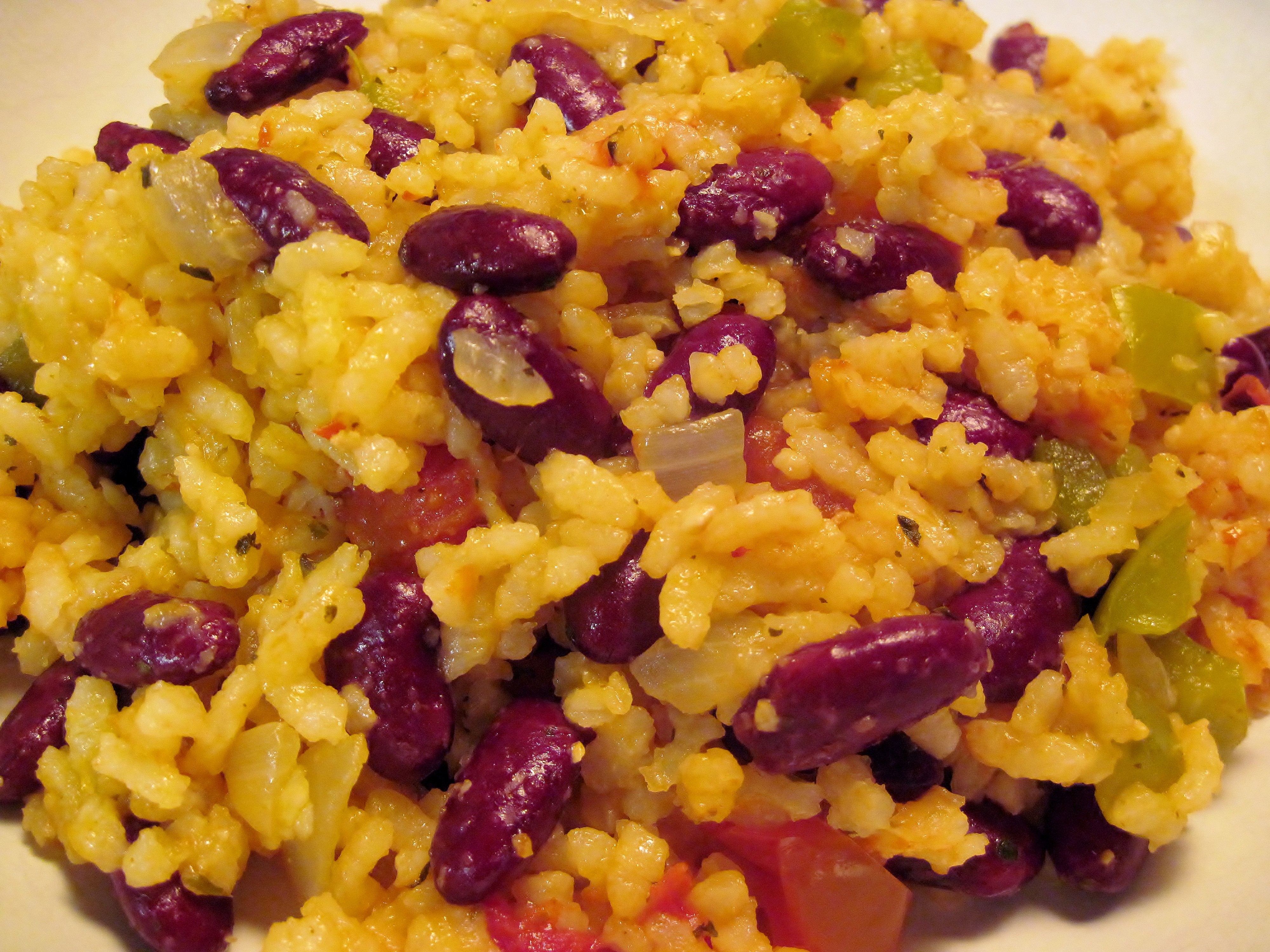 A close-up of rice mixed with red kidney beans, onions, and green peppers, presented in a bowl.